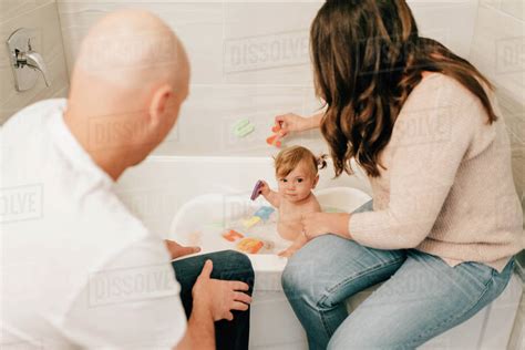 Mother And Father Playing With Baby Daughter In Bath Over