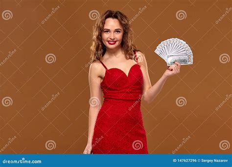 Blond Curly Woman Weared In A Red Dress Is Holding Some Hundred Dollar