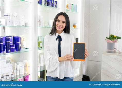 Pretty Beauty Consultant In A White Blouse Showing A Tablet Stock Photo
