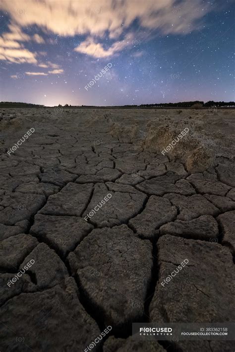 Drought Cracked Lifeless Ground Under Colorful Cloudy Sky At Sunset