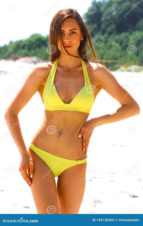 Junge Schöne Sportliche Und Sexy Frau Im Gelben Bikini Der Auf Dem Strand Aufwirft Stockbild