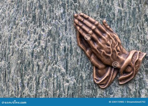 Praying Hands As Bronze Figure On A Graveyard Grave As Religious Symbol