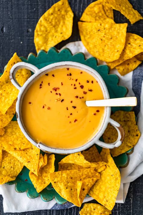 Layered tortilla chips, grated jack cheese, shredded chicken, refried beans, and sour cream are baked to perfection in a tasty appetizer guaranteed to please friends and family. homemade nacho cheese sauce in a bowl, surrounded by ...