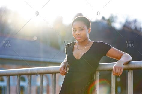 Portrait Of A Young Adult Woman Leaning Against Railing Stock Photo