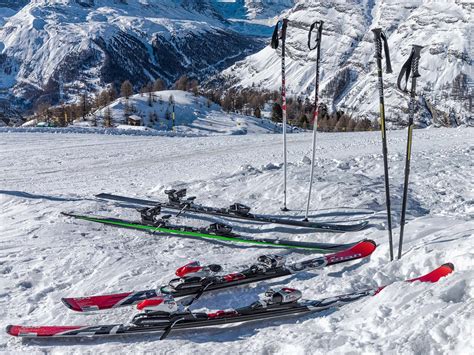 Three Skis And Two Poles In The Snow With Mountains In The Backgroud