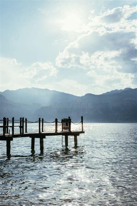 Scenery With Wooden Dock Pier Extending Over Blue Lake Water And