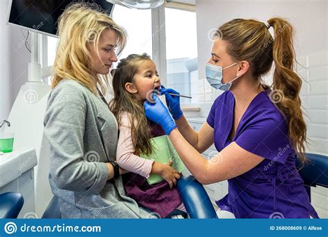 Female Dentist Checks The Patient X S Teeth While Her Mother