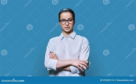 Portrait Of Teenage Female In Eyeglasses With Crossed Arms On Blue