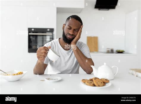 Black Man Yawning Pouring Coffee Away From Cup Stock Photo Alamy