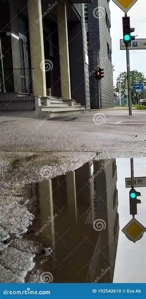 Building And Traffic Light In Reflection In A Puddle On The Pavement