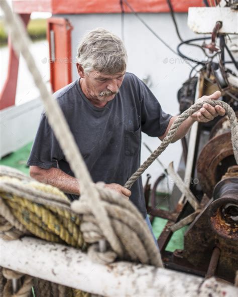 A Commercial Fisherman Loads A Rope Onto A Winch On A Fishing Boat