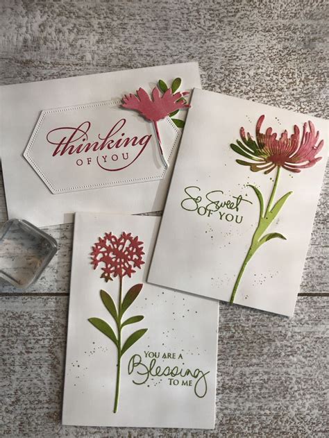 Three Cards With Flowers On Them Sitting Next To A Stamper And Some Inking