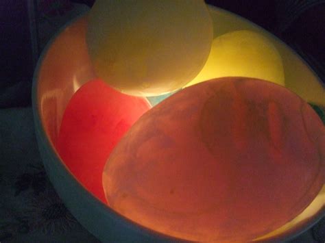 Frozen Water Balloons With Food Colouring In A Bowl With Candles