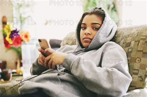 Mixed Race Woman Sitting On Chair Listening To Cell Phone Photo12 Tetra Images Peathegee Inc