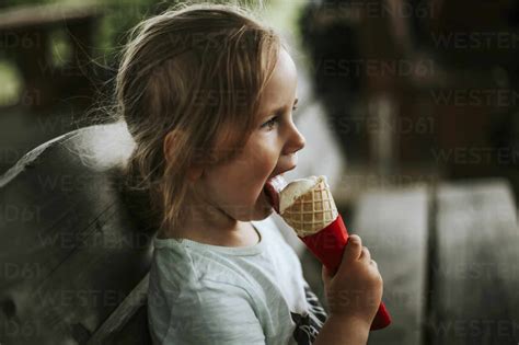 Girl Eating Ice Cream Sitting On Bench Stock Photo