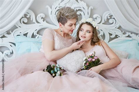 lesbian honeymoon newlyweds in light pink bridal dresses lying on a luxury bed and enjoying