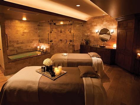 Two Massage Beds With Candles On Them In A Room That Has Stone Walls