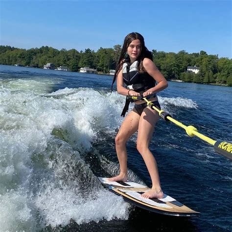 A Girl Is Standing On A Surfboard In The Water While Holding Onto A Rope