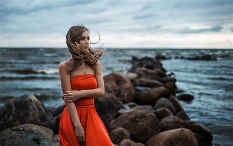 デスクトップ壁紙 女性 モデル ブロンド 被写界深度 遠望する 長い髪 岩 海岸 砂 裸の肩 ウェーブのかかった髪 ビーチ 赤いドレス 風が強い 休暇