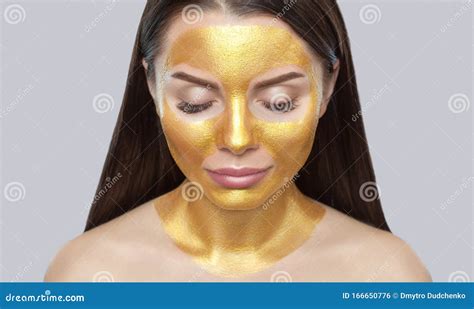 portrait of a brunette woman who makes a golden mask on her face neck and collarbones against