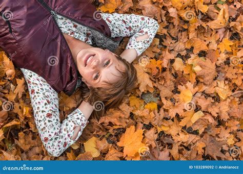 Attractive Woman Is Lying Over Autumn Leaves In Park Stock Photo