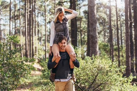Man Carrying His Woman Partner On His Shoulders While Trekking I Stock