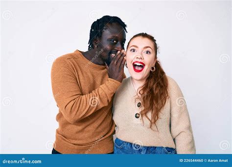 Interracial Couple Wearing Casual Clothes Hand On Mouth Telling Secret