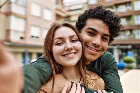 Young Interracial Couple Smiling Happy And Hugging Make Selfie By The Camera At The City Stock
