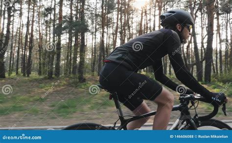 Close Up Shot Of Cyclist Pedaling Bike Wearing Black Jersey Shorts Helmet And Sunglasses Back
