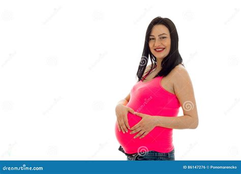 Studio Portrait Of Young Pregnant Brunette Woman In Pink Shirt Touching