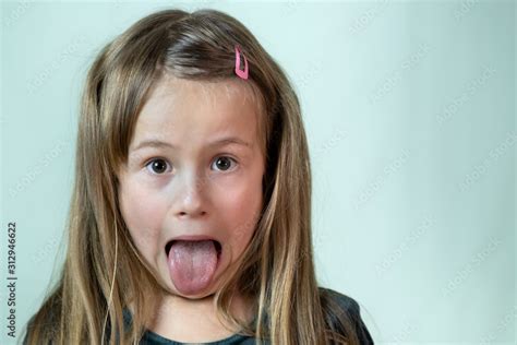 Close Up Portrait Of Little Girl With Long Hair Sticking Out Her Tongue