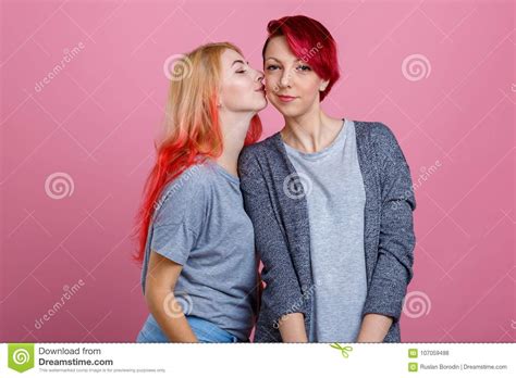 Two Lesbian Girls One Kisses Another On The Cheek On A Pink