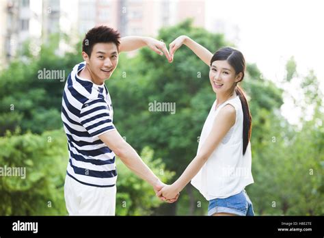 Happy Young Chinese Couple Making Heart Shape With Their Arms Stock