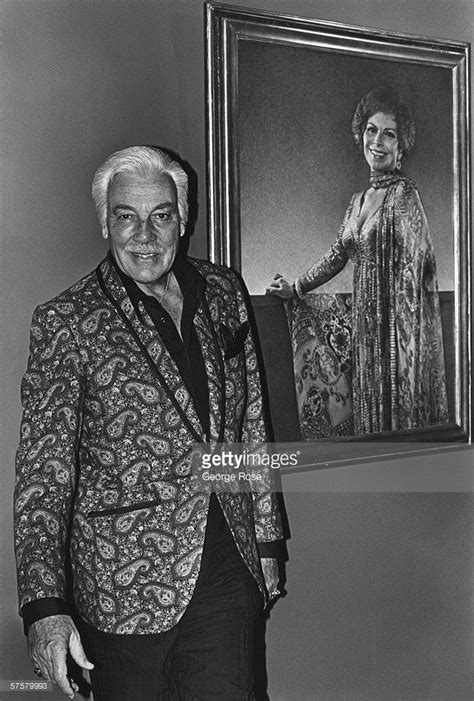 A Man In A Suit Standing Next To A Portrait Of A Woman Holding A Painting