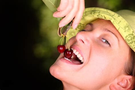 Premium Photo A Young Happy Woman Eating Cherries In The Garden