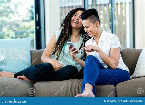 lesbian couple looking at mobile phone and smiling stock image image of indoors hair 66972977