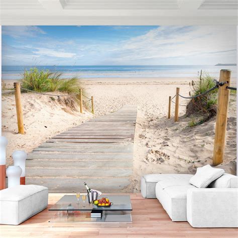 A Living Room Filled With White Furniture Next To A Wooden Walkway Leading To The Beach