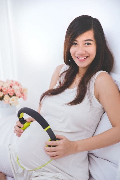 Hermosa Mujer Asiática Embarazada Usando Auriculares En Su Panza Foto