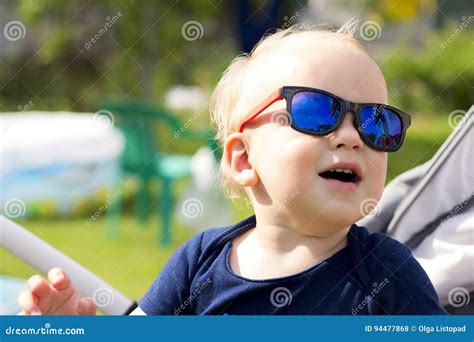 Funny Baby Boy In Sunglasses Sitting Outdoor And Laughing Stock Photo