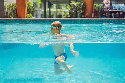 Boy Having Fun Playing Underwater In Swimming Pool On Summer Vacation