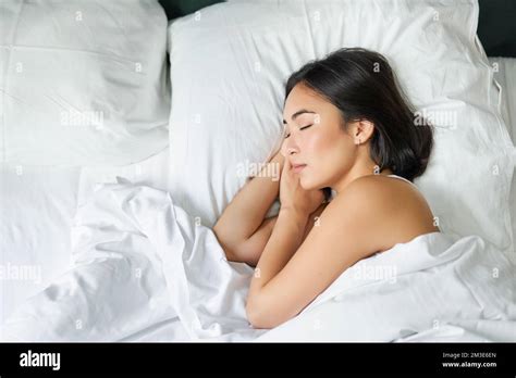 Top View Image Of Asian Woman Sleeping Alone In King Size Bed On White