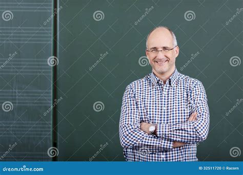 Professor With Arms Crossed Standing Against Chalkboard Stock Photo