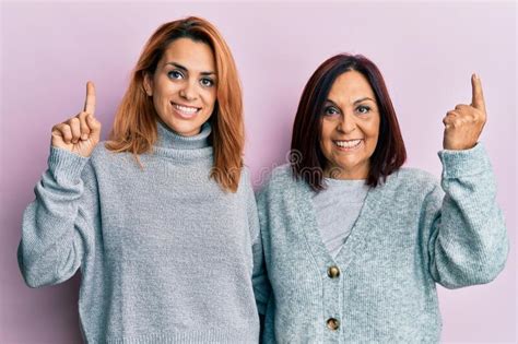 Latin Mother And Daughter Wearing Casual Clothes Smiling Amazed And Surprised And Pointing Up