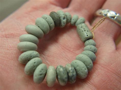 A Close Up Of A Persons Hand Holding A Bracelet Made Out Of Stones