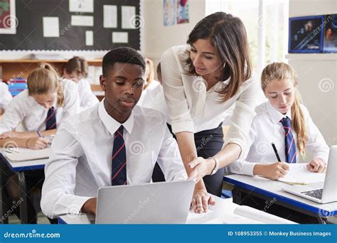 Female Teacher Helping Pupil Using Computer In Classroom Stock Image