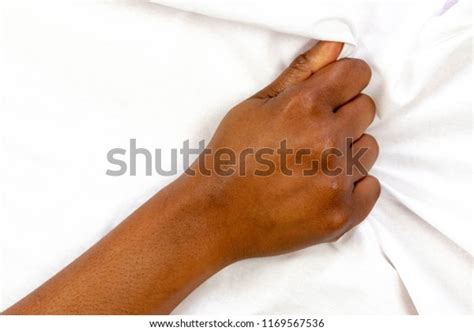 hand sign orgasm of black woman pulling white sheets on bed in hotel hand of african american