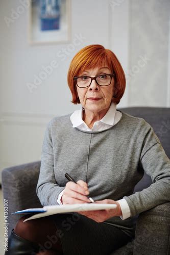 Portrait Of Mature Psychologist In Eyeglasses Sitting On Comfortable