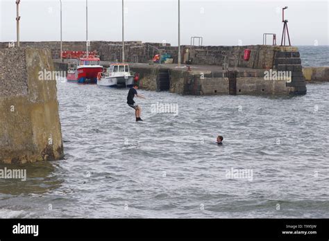 Two Teenage Lads Jumping From The Harbour Wall Into The Sea At St