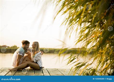 Romantic Couple Sitting On The Wooden Pier On The Lake Stock Image Image Of Embracing