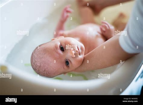 Unrecognizable Mother Bathing Her Son In White Small Plastic Bat Stock